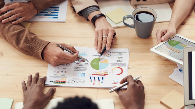 Group studying printed data on a conference table for a daily sales report