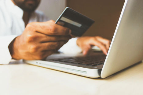 person holding a credit card in front of a laptop