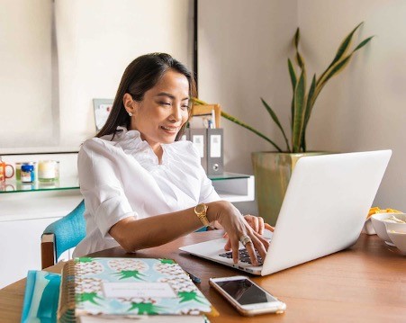 A professional woman sitting by a laptop doing email marketing activities