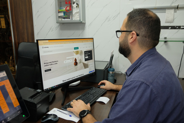 Maen Abbasi using the GoDaddy Website Builder at work to process orders