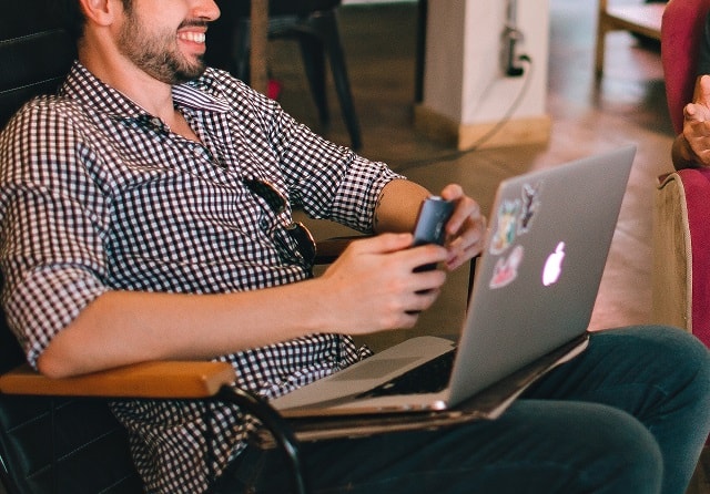 find international customers using social media man sitting at the computer with mobile phone in hand