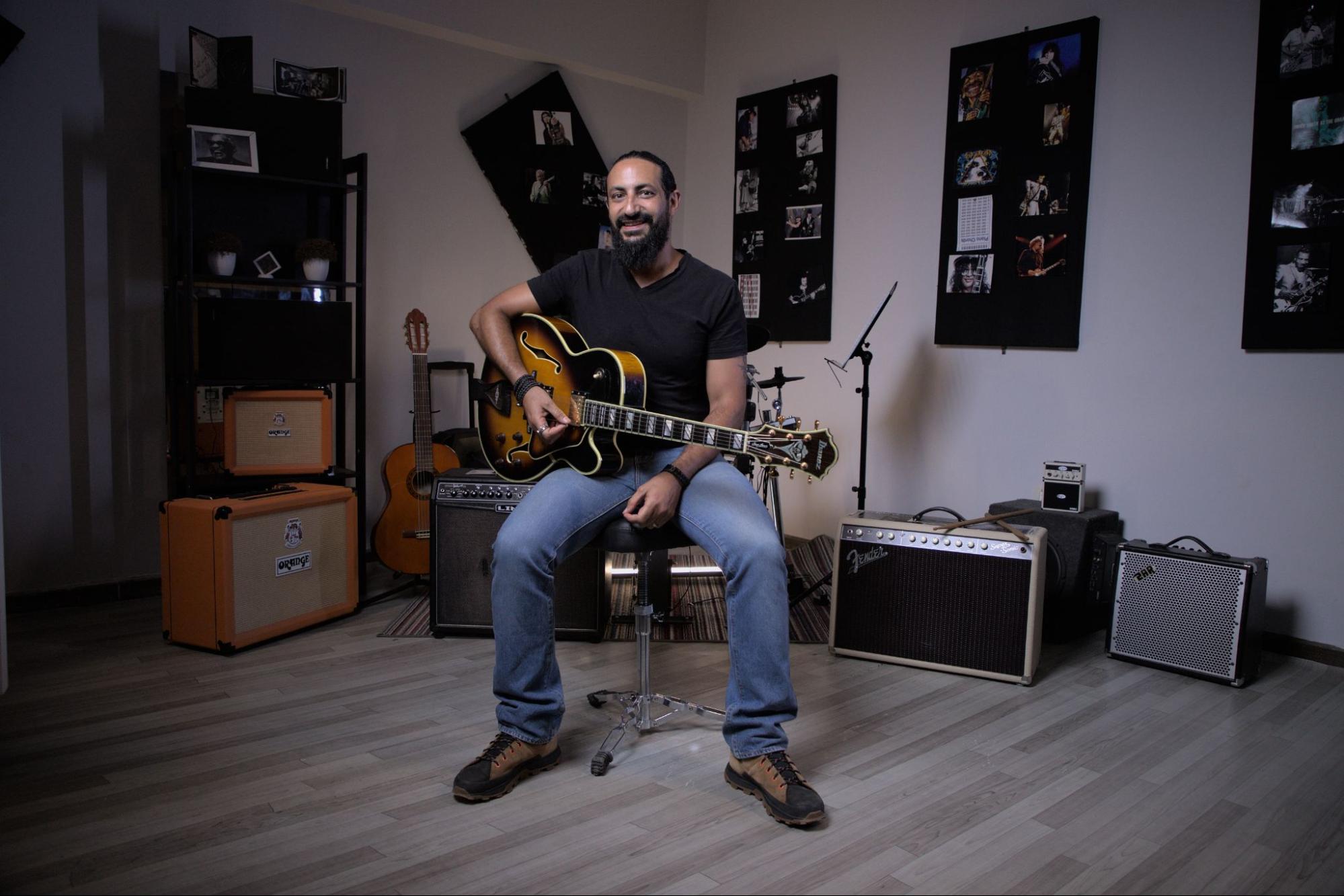 Sherif Watson, CEO of Pocket music school sitting with his guitar