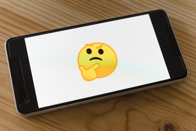 Mobile phone with thinking emoji on screen