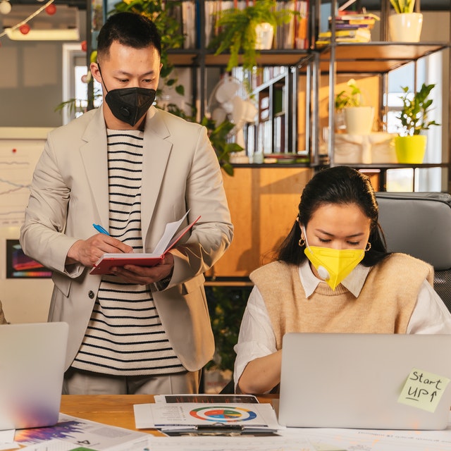 Domain Name Man Standing Taking Notes and Woman Using Laptop