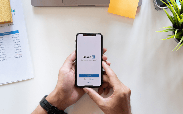 Hands Holding An Iphone Showing LinkedIn Page