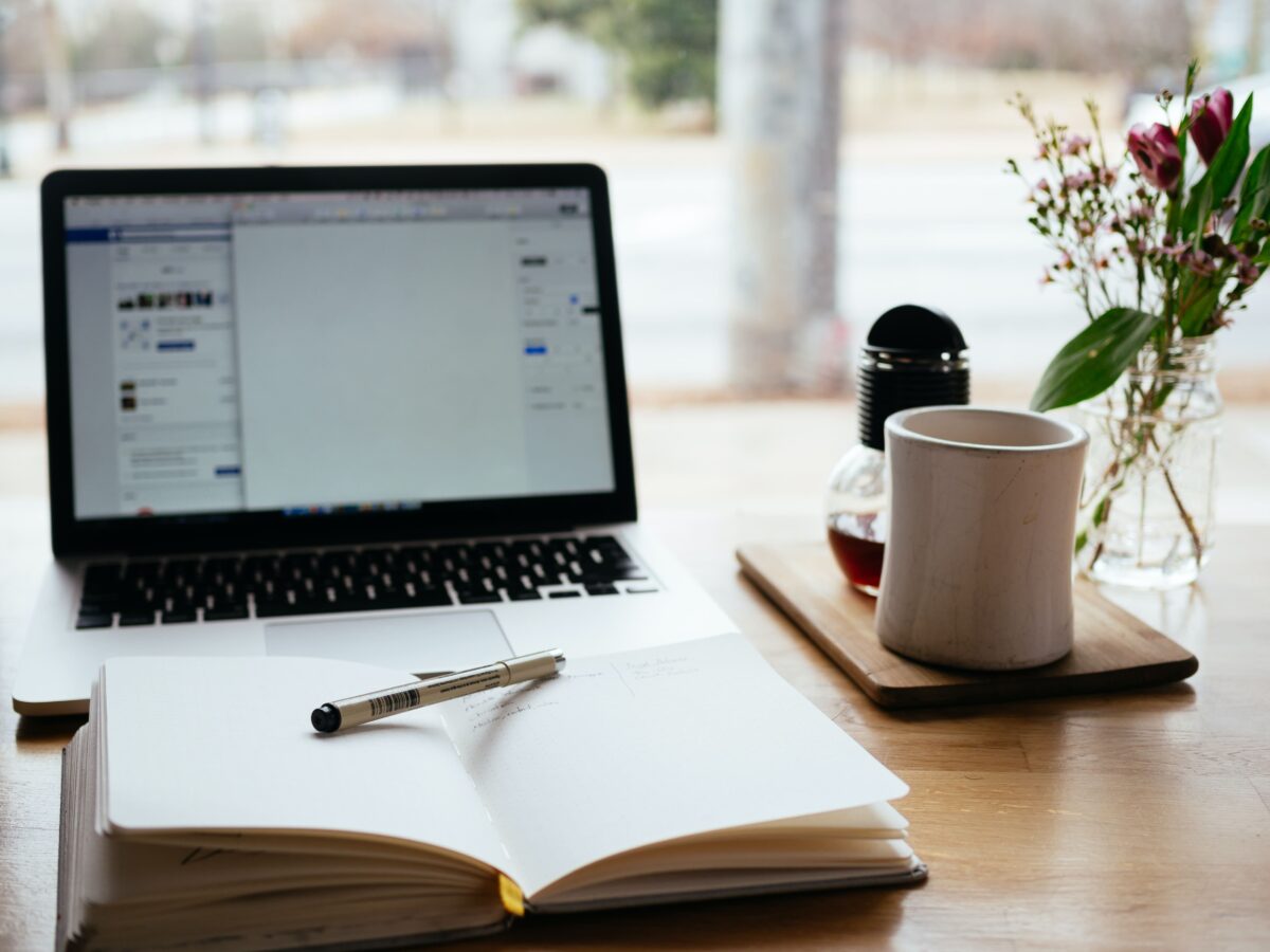 Mug next to an open laptop and notepad