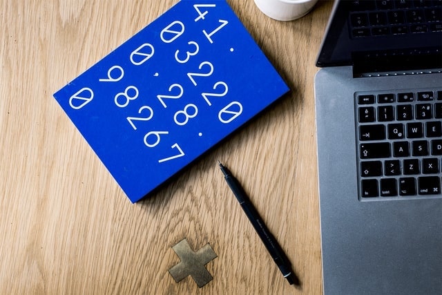 Blue Calculator Sitting on Desk Next to a Laptop