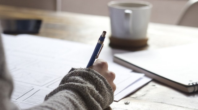 Business Finance Person Writing at Desk