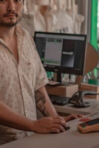 Cashier Standing Beside Computer and Card Reader