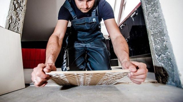 Man in Overalls Laying Tile