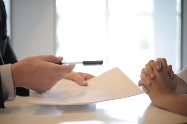 Business person offering pen and paper to client