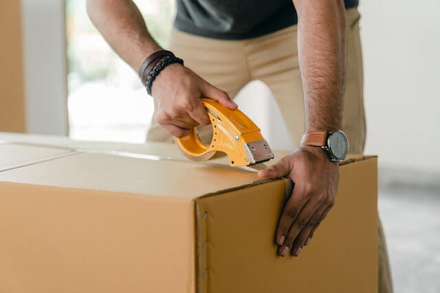 Close-up of a man taping up a shipping box