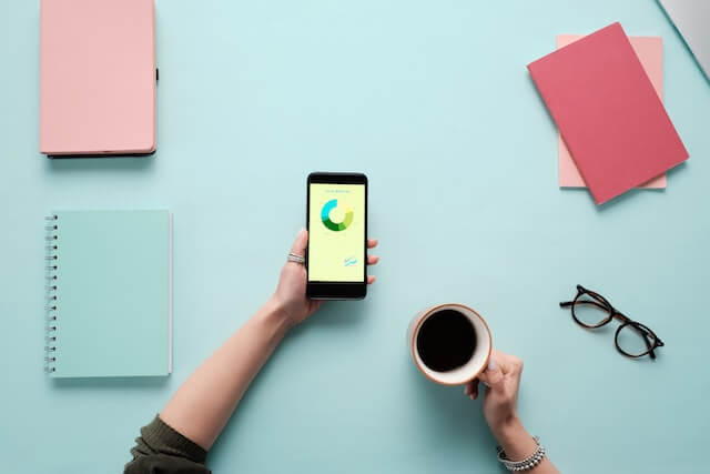 Person holding smartphone with graphs on the screen