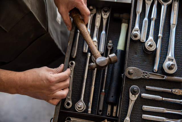 Someone picking up a hammer from a toolbox.