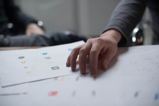 Someone’s hand resting on papers with various logo designs