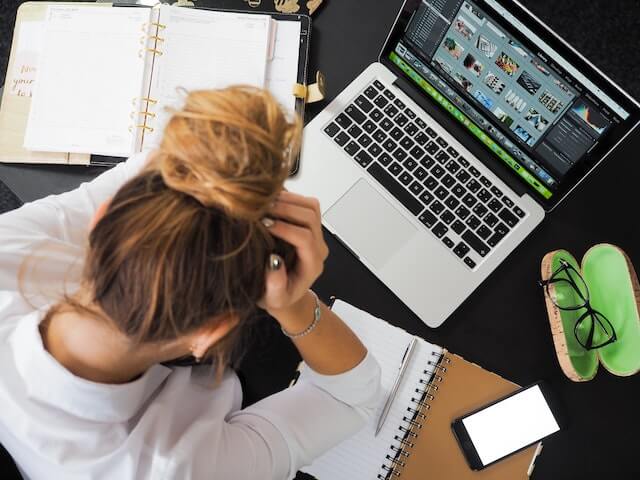 Woman with her head in her hands sitting at a desk