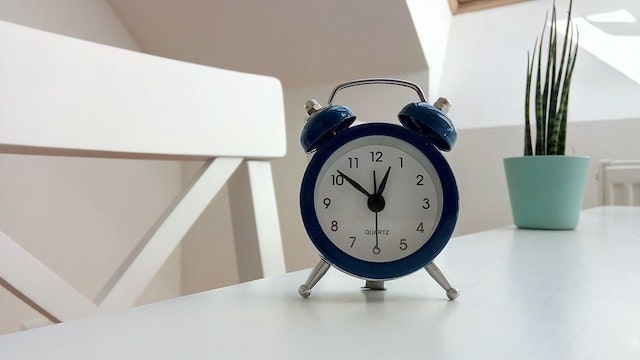 Blue alarm clock sitting on white desk