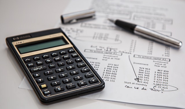 Calculator and budget sheet with pen in the background