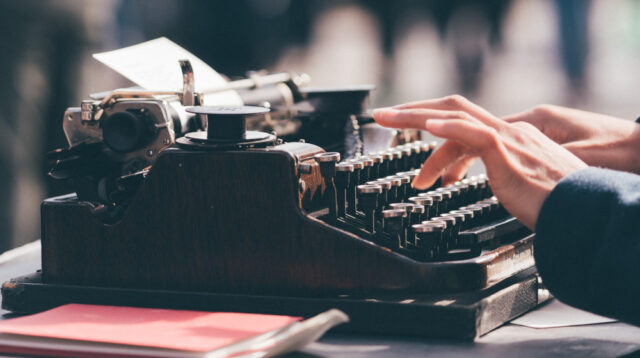 Person typing on a black typewriter