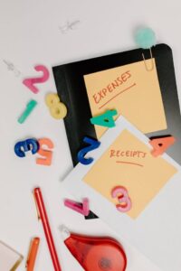 Folders on desk with office supplies and sticky notes that read “expenses” and “receipts”