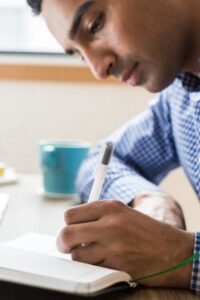 Man at Desk Writing in Notebook