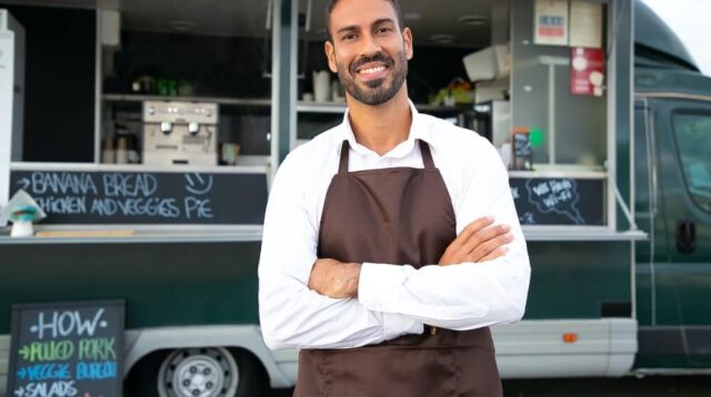 Man in apron standing in front of food truck