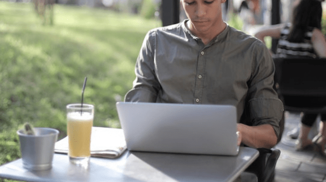 Man using a laptop at an outdoor cafe