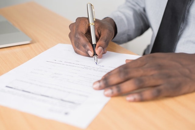 Person filling out paperwork on desk