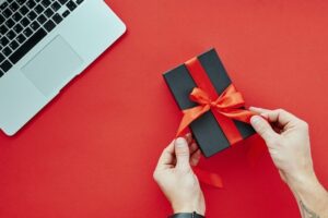 Person tying a red ribbon on a gift box