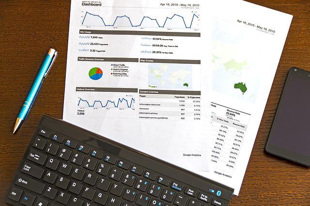 Printed reports on desk next to keyboard and pen