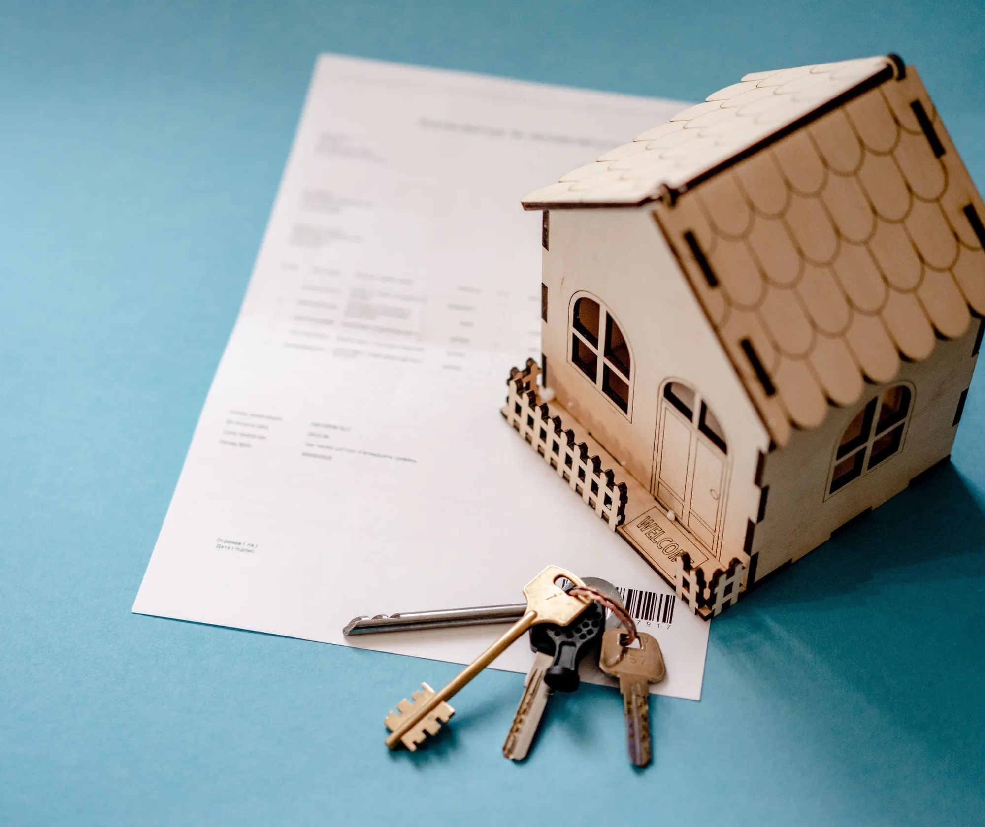 Tiny wooden house sitting atop mortgage documents