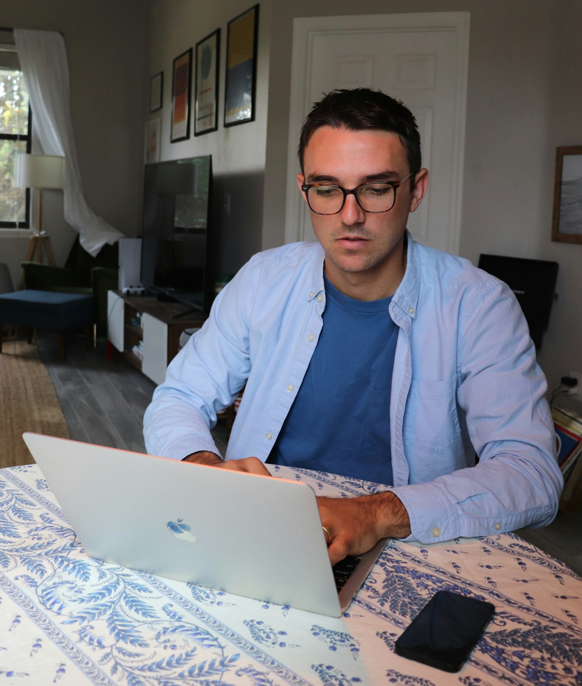 Man in sky blue shirt working at a laptop