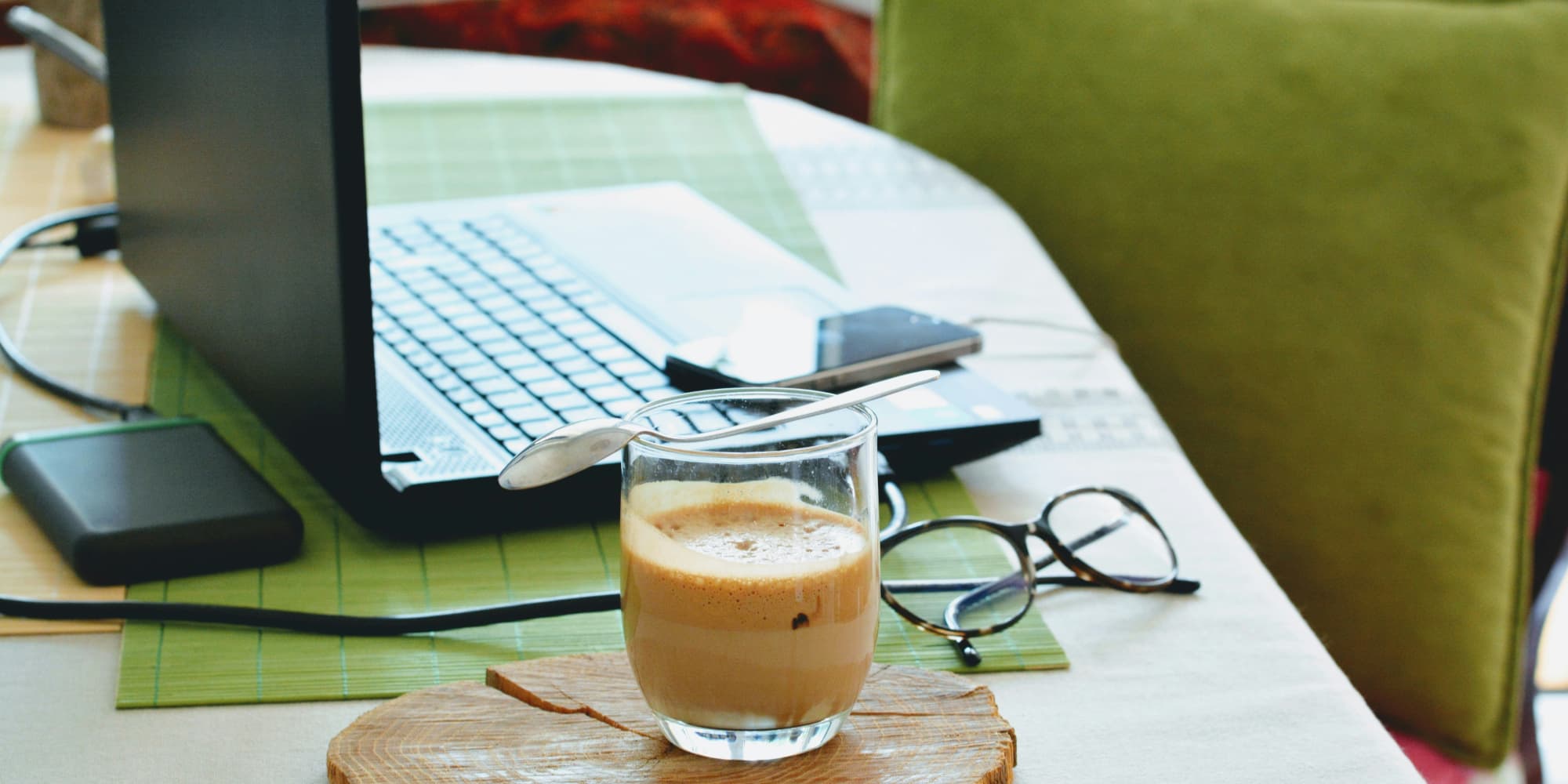 White desk with a laptop, a phone and a latte