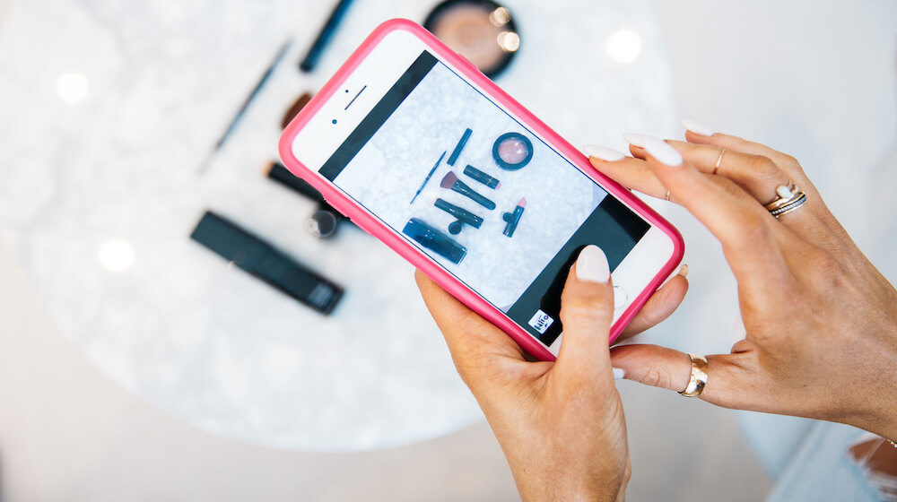 Person taking photos of makeup products on a cell phone