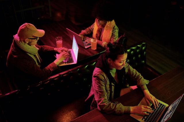 Three people typing on laptops in close proximity to one another