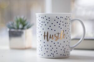 White mug with the word hustle on it