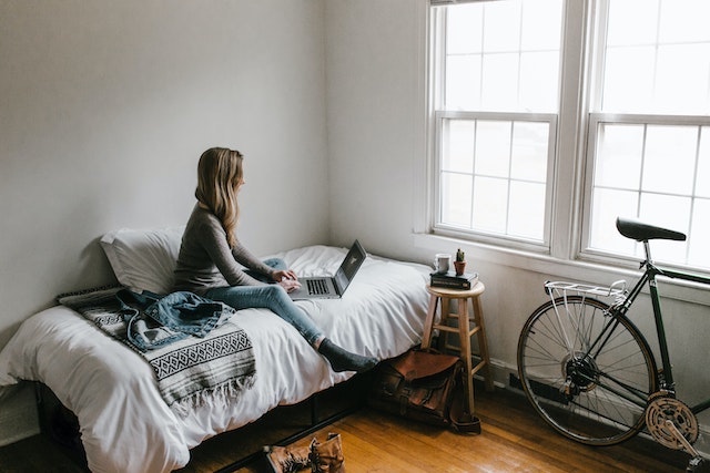 Woman sitting on bed working on a laptop