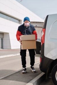 Masked man unloading boxes from truck