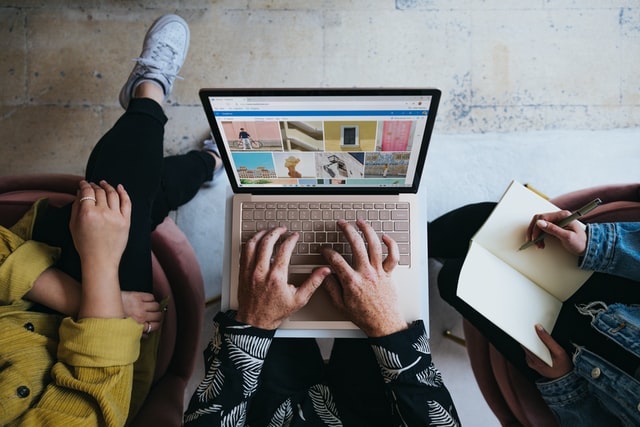 Overhead view of three people gathered around a laptop.