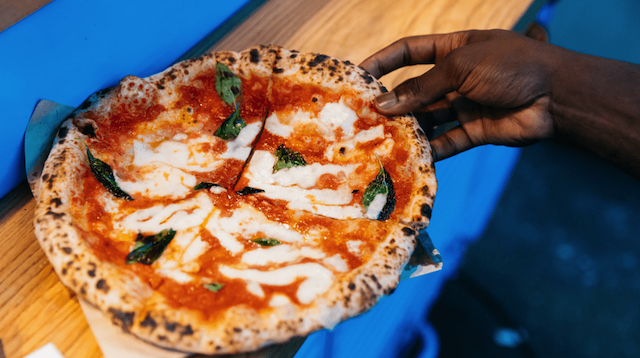 Person Holding a Fresh Pizza