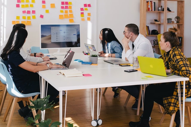 Small team sitting around a table looking at a monitor illustrating how to goal set