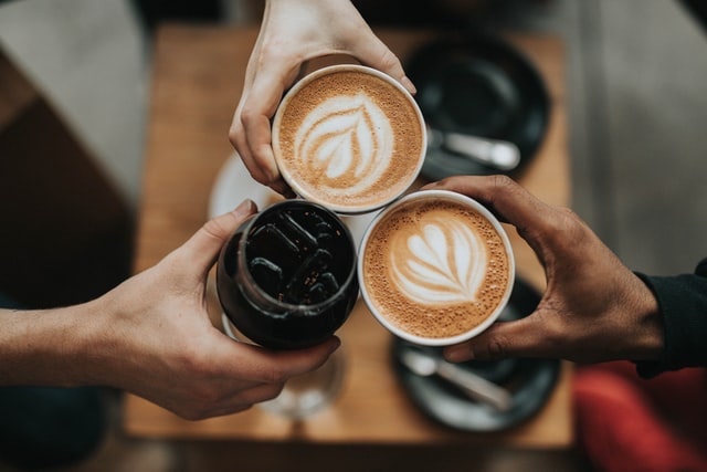 Three People Clinking Coffee Cups as a Toast