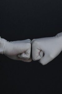 Two People Wearing Gloves Fist Bumping