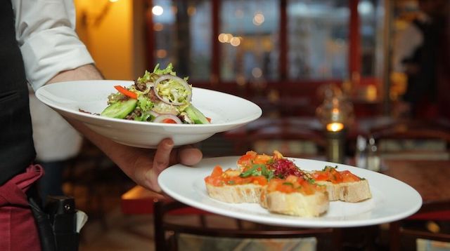 Waiter Holding Two Plates of Food in One Hand