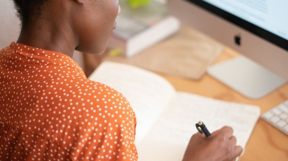 Woman in orange shirt working at desk.