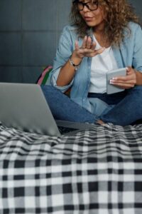 Woman Sitting on Bed Talking to Someone on Her Laptop