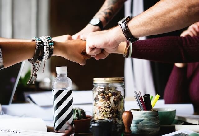 Close-up view of people fist bumping in an office setting