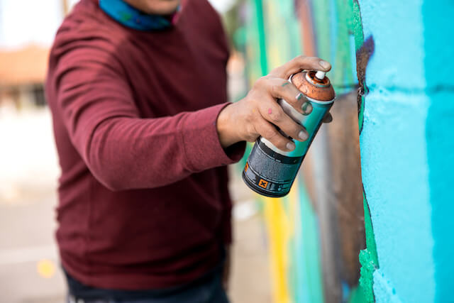 Person with can of spray paint spraying a wall