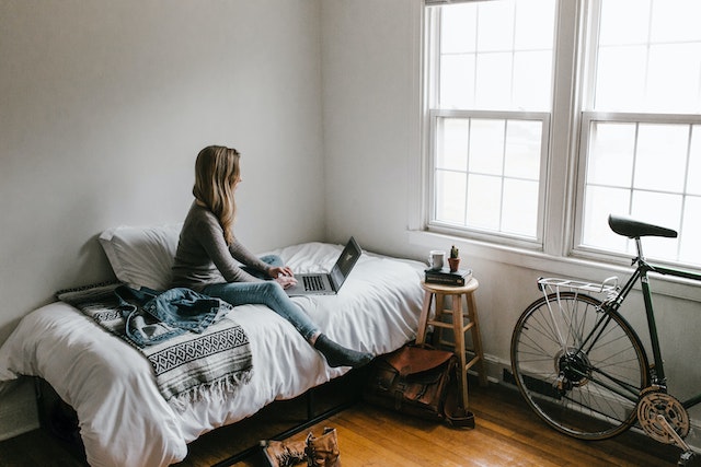 Woman working on laptop while sitting on her bed