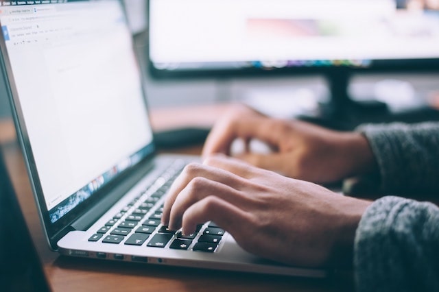 Close-up of person typing on a laptop